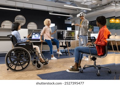 Business colleagues in office watching man using vr headset, asian woman in wheelchair, inclusivity. modern office environment with open workspaces and casual seating arrangements, unaltered - Powered by Shutterstock