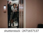Business colleagues reviewing documents together in elevator.