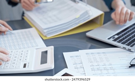 Business colleagues reviewing financial documents and calculating taxes. Auditor inspecting financial reports with magnifying glass. Business audit, taxes and forensic accounting concept - Powered by Shutterstock