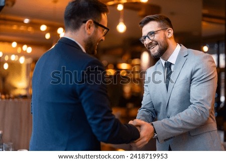 Business colleagues shaking hands in a co-working office. Happy businessmen greeting each other at the meeting.