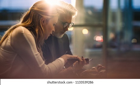 Business colleagues sitting together in office lobby and using their mobile phones. Business professionals using cell phones during a break in office. - Powered by Shutterstock