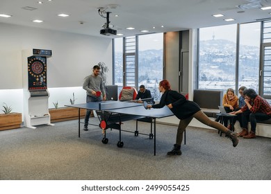  Business colleagues take a break from work to enjoy a game of table tennis, fostering teamwork and camaraderie in the workplace - Powered by Shutterstock