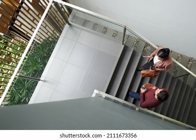 Business colleagues with take out coffee walking up the stairs and discussing work, view from the top - Powered by Shutterstock