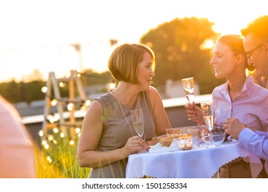 Business Colleagues Talking While Standing At Table During Rooftop Party