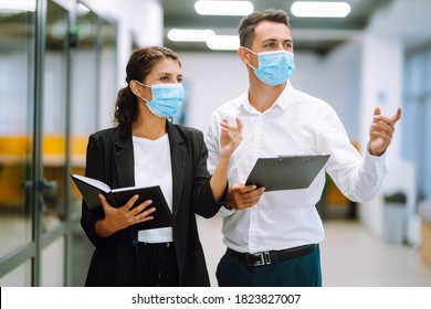 Business colleagues wearing medical face mask discussing together work issues at office. Teamwork during pandemic in quarantine city. Covid-19. - Powered by Shutterstock