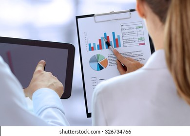 Business colleagues working and analyzing financial figures on a graphs - Shutterstock ID 326734766