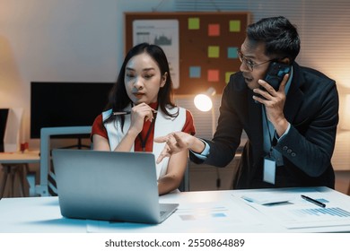 Business colleagues working late and having a stressful phone call while discussing over a laptop - Powered by Shutterstock