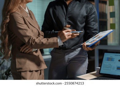 Business colleagues working late, reviewing graphs and charts on documents and digital tablet, analyzing financial data - Powered by Shutterstock