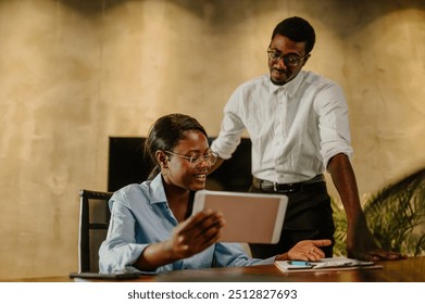 Business colleagues working together on a digital tablet while at the office. Diverse creative executives talking about their new project. Focus on an african american business woman holding a tablet. - Powered by Shutterstock