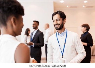 business, communication and education concept - international group of people with conference badges drinking coffee and talking at brake - Powered by Shutterstock