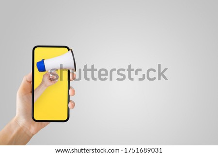 Business Communication and Marketing Concept : Hand holding megaphone in smartphone for announcement and advertisement concept.