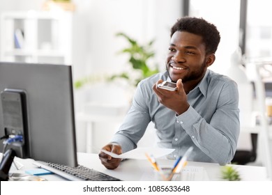 business, communication and technology concept - african americanbusinessman with papers and computer calling or using voice recorder on smartphone at office - Powered by Shutterstock