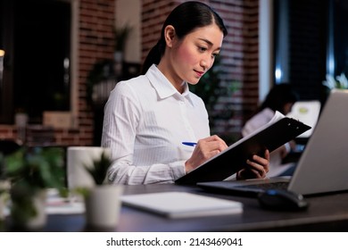 Business Company Employee In Office Workspace Signing Startup Project Documentation. Financial Advisor With Clipboard Reviewing Marketing Campaign Paperwork While Analyzing Accounting Data.