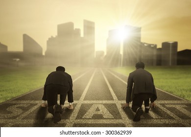 Business competition: Rear view of two worker wearing formal suit and kneeling on the start line to compete