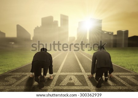 Business competition: Rear view of two worker wearing formal suit and kneeling on the start line to compete