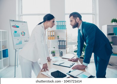Business competition, side view profile of two colleagues in classy suits having disagreement and conflict, standing in modern work station, place, face to face, lean with hands on the table