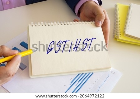 Business concept about GSTHST Goods Services Tax Harmonized Sales Tax with inscription on the notepad. 
