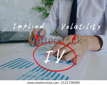 Business concept about IV Implied Volatility with handwritten acronym.Busy businessman under stress due to excessive work on background.
