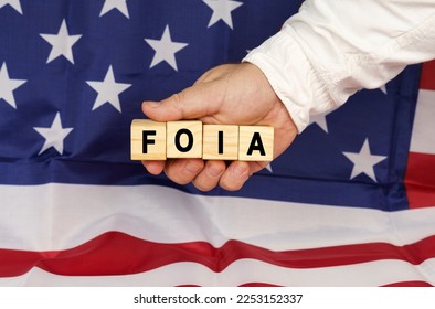 Business concept. Against the background of the USA flag, a man's hand with cubes with the text - FOIA