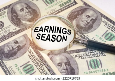 Business concept. Among the dollars lies a magnifying glass with the inscription - Earnings Season