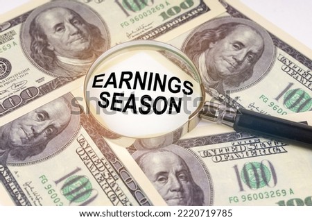 Business concept. Among the dollars lies a magnifying glass with the inscription - Earnings Season