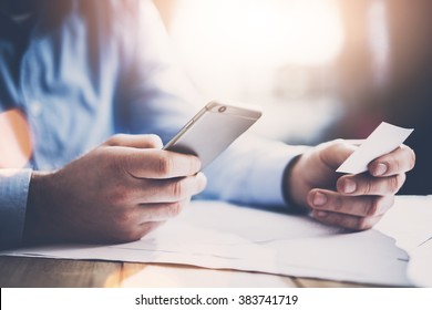 Business concept. Businessman holding hand white businesscard and making photo smartphone. New work project on the table. Horizontal mockup. Blurred effect
