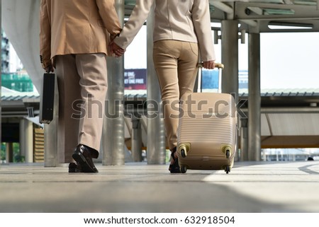 Business concept : Businessman and business woman  are walking hand in hand at the airport terminal 