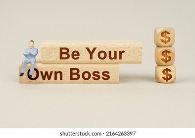 Business concept. Cubes with the image of the symbol of the dollar, on the blocks with the inscription - Be Your Own Boss, sits a figure of a businessman.