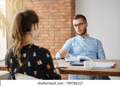 Business Concept. Dark-haired Anonymous Woman Sitting At Table In Office In Front Of Serious Mature Human Resources Manager, Speaking About Work Responsibilities During Job Interview.