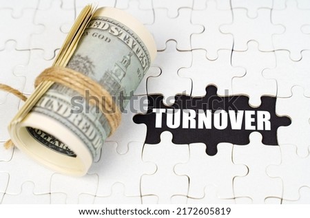Business concept. Dollars lie on white puzzles, on a black surface there is an inscription - Turnover