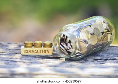 Business Concept - EDUCATION WORD Golden coin stacked with wooden bar on shallow DOF green background.