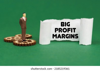 Business concept. The figure of a man stands on the gears and reads the inscription - Big Profit Margins on paper - Shutterstock ID 2185219361