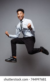 Business Concept - Full length portrait of successful african american businessman happy jumping in the office. 