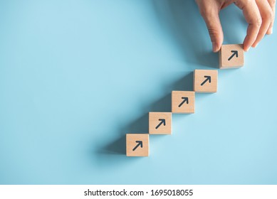 Business concept growth success process, Close up Woman hand arranging wood block stacking as step stair on paper blue background, copy space.