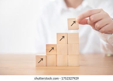 Business concept growth success process, Businesswoman hand arranging wood cube stacking as step stair with arrow up symbol.