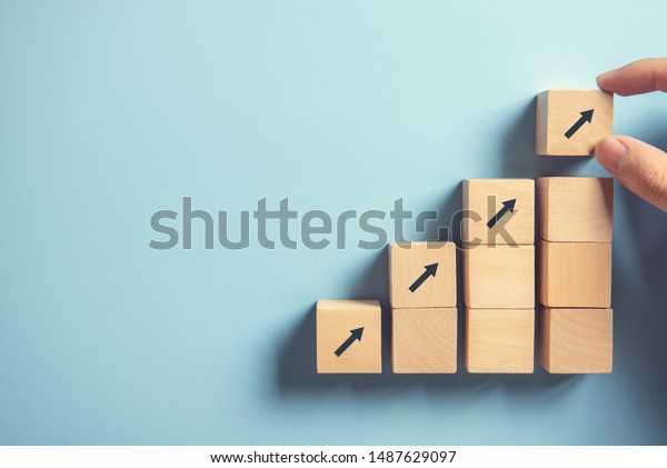 Business concept growth success process, Close up\
Woman hand arranging wood block stacking as step stair on paper\
blue background, copy\
space.