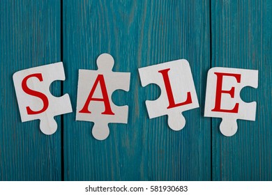 Business Concept - Jigsaw Puzzle Pieces with text "SALE" on blue wooden background