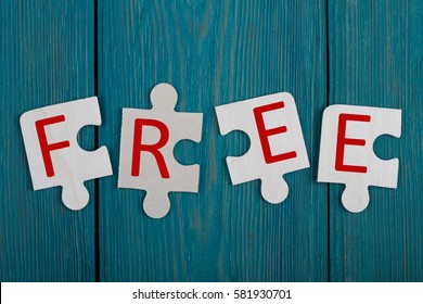 Business Concept - Jigsaw Puzzle Pieces with text "FREE" on blue wooden background
