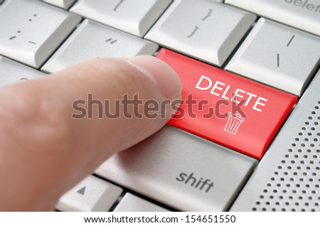 Business concept male finger pointing delete key on  a metallic keyboard