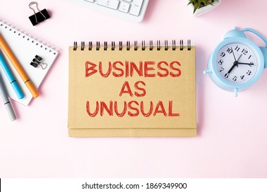 Business Concept. Notepad With Text Business As Unusual Notepad, Keyboard, Alarm Clock, Markers, Notepad, On A Pink Background