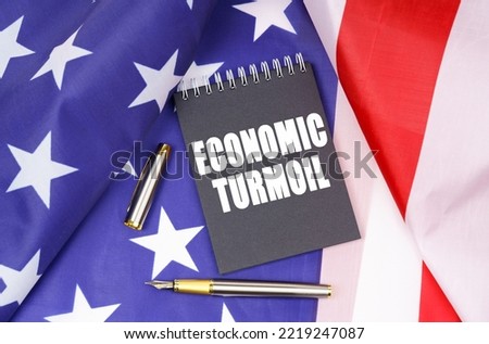 Business concept. On the American flag lies a pen and a notebook with the inscription - economic turmoil