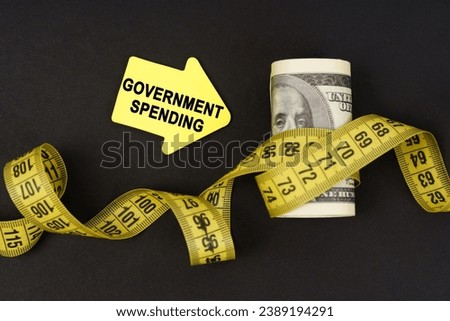 Business concept. On a black surface there are dollars wrapped in measuring tape and stickers with the inscription - government spending