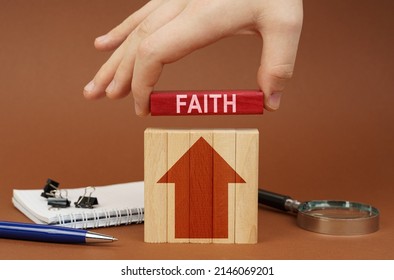 Business Concept. On A Brown Surface Are Office Items, Wooden Blocks, In The Hand Is A Red Block With The Inscription - Faith