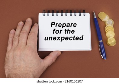 Business Concept. On A Brown Surface Are Coins, A Pen And A Notepad With The Inscription - Prepare For The Unexpected. The Notebook Is Holding A Hand.