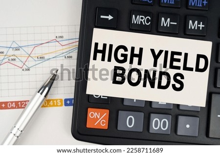 Business concept. On the business chart lies a pen, a calculator and a business card with the inscription - high yield bonds