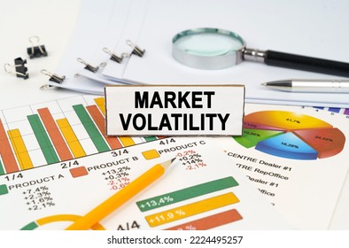 Business concept. On the business charts lies a magnifying glass, a pen and a sign with the inscription - Market Volatility