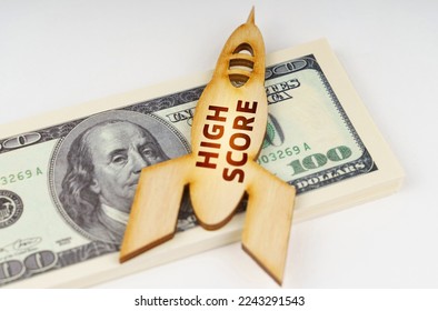 Business concept. On the dollars lies a wooden model of a rocket with the inscription - High Score. Image is partially blurred