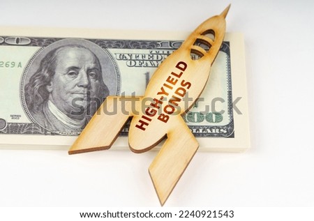 Business concept. On the dollars lies a wooden model of a rocket with the inscription - High-Yield Bonds