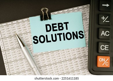 Business concept. On financial reports lies a calculator, a pen and a sticker with the inscription - Debt solutions - Shutterstock ID 2251611185
