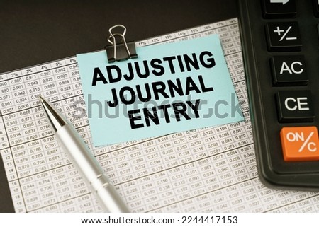 Business concept. On financial reports lies a calculator, a pen and a sticker with the inscription - Adjusting Journal Entry
